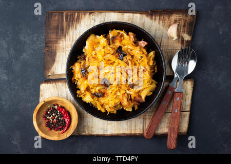 Piatto tradizionale della cucina polacca - Bigos dal cavolo cappuccio fresco, carne e prugne. Vista dall'alto. Sfondo scuro. Foto Stock