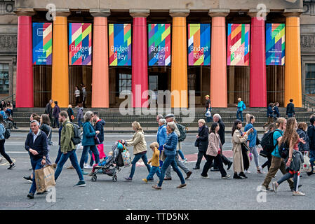 Pedoni su Princes Street a piedi dalla parte anteriore della Royal Scottish Academy building pubblicità il 2019 Mostre estive di Bridget Riley. Foto Stock