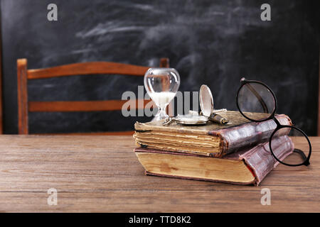 Composizione vintage di vecchi libri, occhiali e clessidra sul tavolo di legno Foto Stock