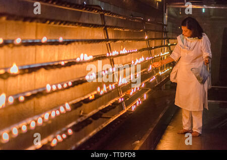 Una donna accende una candela in un tempio in Kataragama, Sri Lanka Foto Stock