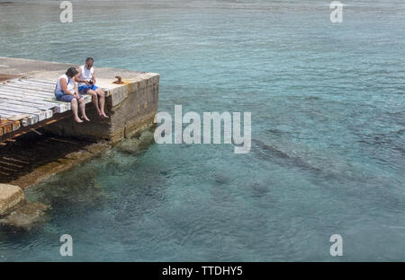 SANTA PONSA, MALLORCA, Spagna - 29 Maggio 2019: rilassato giovane seduto su un ponte di legno dall'acqua su 29 Maggio 2019 a Santa Ponsa, Mallorca, Spagna. Foto Stock