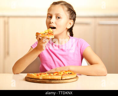 Bambina di mangiare la pizza a casa Foto Stock