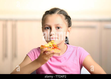 Bambina di mangiare la pizza a casa Foto Stock