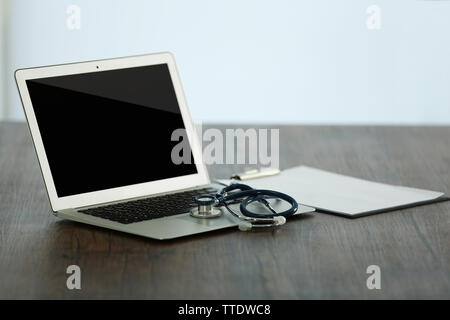 Computer portatile con uno stetoscopio e sangue misuratore di pressione sul tavolo di legno in office Foto Stock