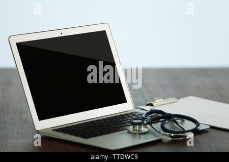 Computer portatile con uno stetoscopio e sangue misuratore di pressione sul tavolo di legno in office Foto Stock