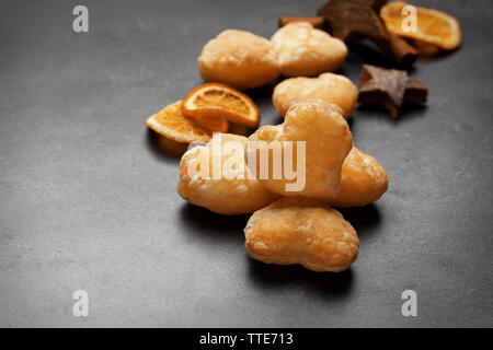 A forma di cuore biscotti con spezie secche su sfondo grigio scuro Foto Stock