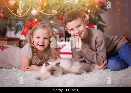 I bambini e il sonno gatto in decorata sala di Natale Foto Stock