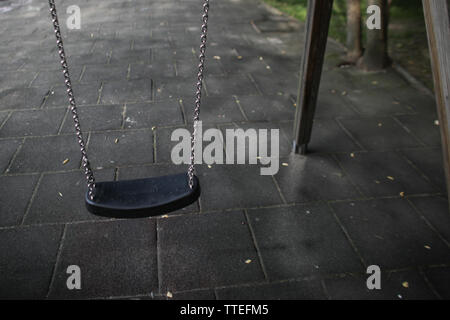 Ragazza giovane oscillanti in un parco giochi per bambini senza nessuno attorno a. Foto Stock