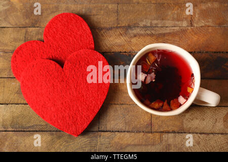 Tazza di tè di frutta con due cuori rossi su sfondo di legno closeup Foto Stock