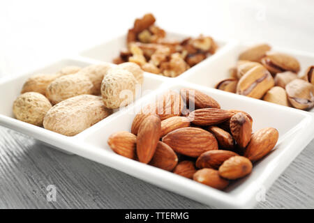 Gherigli di noce, mandorle, pistacchi, arachidi in ceramica piastra rettangolare, close-up Foto Stock