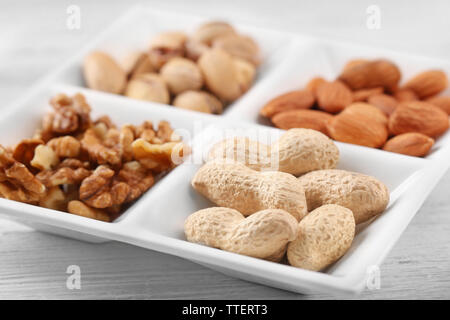 Gherigli di noce, mandorle, pistacchi, arachidi in ceramica piastra rettangolare, close-up Foto Stock