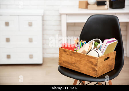 Scatola di legno con cose per trasferimenti sulla sedia nero Foto Stock