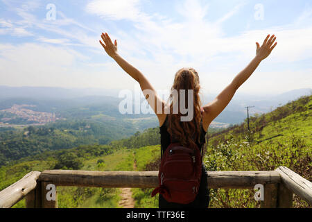 Escursionista donna in piedi con le mani fino raggiungere la cima. Ragazza accoglie un sun. Donna di successo escursionista braccia aperte sulla cima della montagna. Ragazza per godersi la natura su J Foto Stock