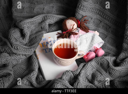 Rag Doll con favole prenota e la tazza di tè su copriletto. Concetto di infanzia Foto Stock