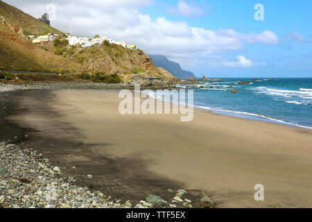 Playa de Almaciga bella spiaggia di sabbia nera con il villaggio di Almaciga sulla collina, Tenerife, Spagna Foto Stock