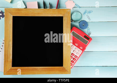 Piccola scuola di blackboard con cancelleria su sfondo di legno Foto Stock