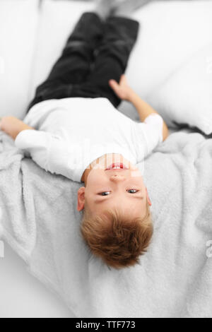 Ritratto di carino allegro ragazzo disteso capovolto sul divano in camera Foto Stock