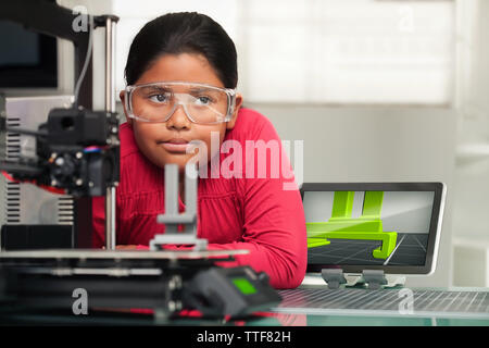 Un simpatico bambina in studio pensa di impostazione di idee per il suo 3d disegno stampato che è in fase di stampa in primo piano. Foto Stock