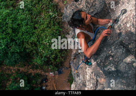 Donna corda di clipping mentre arrampicata su roccia calcarea in Vietnam Foto Stock