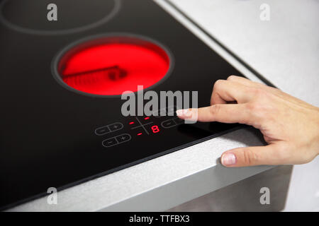 Femmina gira a mano sul piano di cottura elettrico closeup Foto Stock