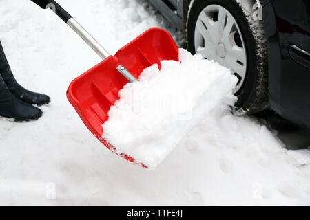 La donna la rimozione di neve con la pala accanto a AUTO Foto Stock