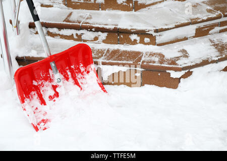 Pala di rosso per la rimozione della neve accanto a scale Foto Stock