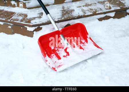 Pala di rosso per la rimozione della neve accanto a scale Foto Stock