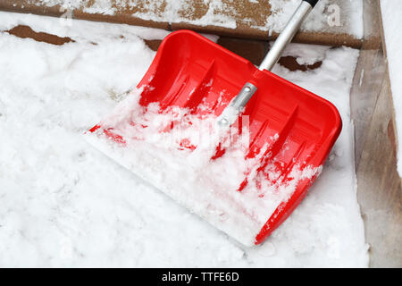 Pala di rosso per la rimozione della neve accanto a scale Foto Stock