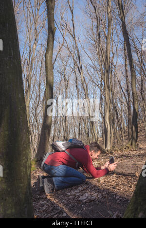 L uomo è fotografare fiori di primavera nella foresta con la sua mobil Foto Stock