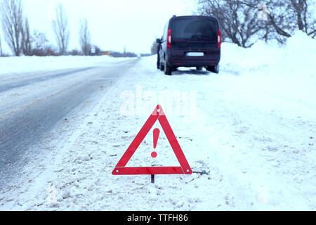 Ripartizione per auto con il triangolo rosso in inverno nevoso road, all'aperto Foto Stock