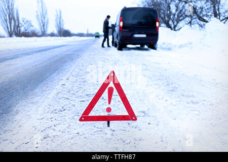 Ripartizione per auto con il triangolo rosso in inverno nevoso road, all'aperto Foto Stock