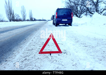 Ripartizione per auto con il triangolo rosso in inverno nevoso road, all'aperto Foto Stock