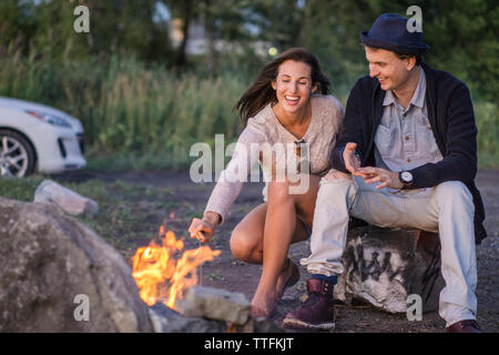 Amici in un viaggio su strada la cottura di marshmallows sul fuoco Foto Stock