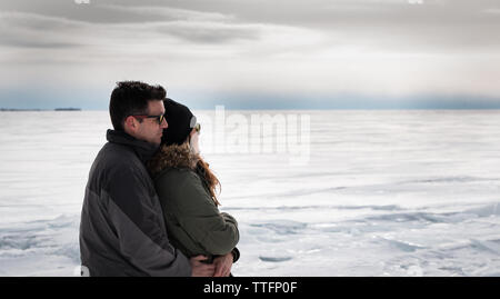 Giovane abbracciando come appaiono su un lago ghiacciato in un giorno d'inverno. Foto Stock
