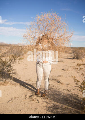Una giovane donna detiene un tumbleweed fino davanti al suo volto. Foto Stock