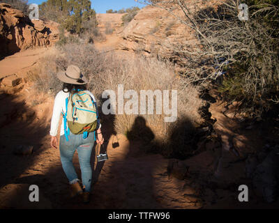 Una donna con un cappello e una macchina fotografica escursioni attraverso il paesaggio del deserto. Foto Stock