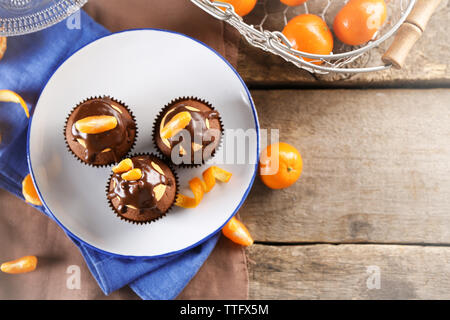 Tre gustose tortine con fettina di mandarino e cioccolato su una piastra su sfondo di legno Foto Stock
