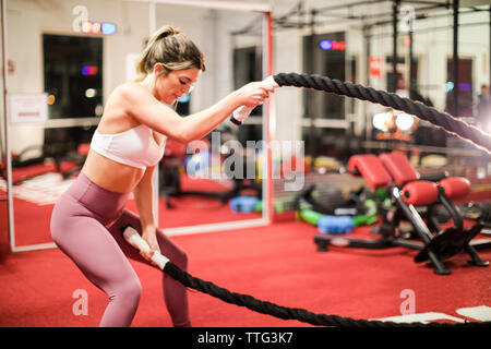 Montare la donna facendo battaglia corda esercizio in palestra Foto Stock