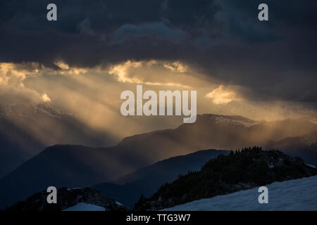 Raggi di sole che splende attraverso le nuvole in un paesaggio di montagna. Foto Stock