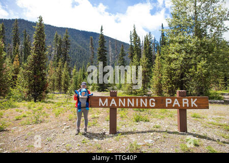 La madre e il Bambino accanto a Manning Park segno durante una vacanza Foto Stock