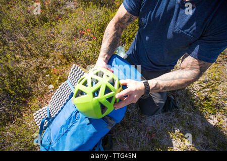 Alpinista smette di mettere il suo casco prima di scalare una montagna. Foto Stock