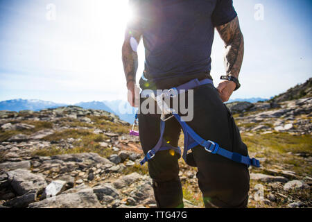 Un scalatore cinghie sul suo cablaggio prima di arrampicata in B.C., Canada. Foto Stock