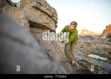 Uomo attivo salendo sul grande masso in Costa montagne, B.C. Foto Stock