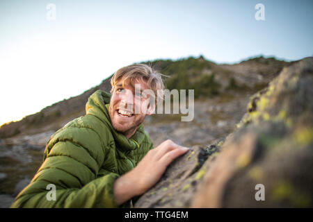 Vista laterale di uomo felice arrampicata su roccia. Foto Stock