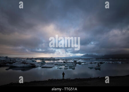 Silhouette uomo in piedi dal mare contro cloudscape Foto Stock