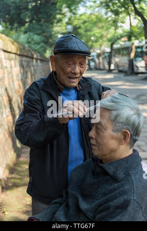 Ritratto di barbiere lavorando sulle strade di Hanoi, Vietnam Foto Stock