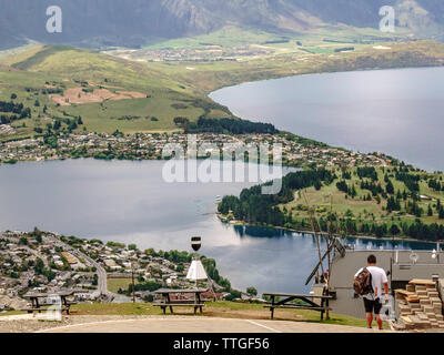 Giovane uomo sulla montagna porta nelle viste sopra Queenstown, Nuova Zelanda Foto Stock