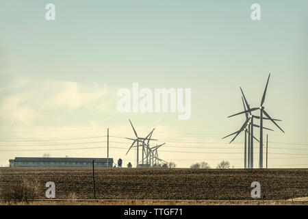 Le turbine eoliche che ruota sopra il campo di fattoria nel Midwest americano Foto Stock