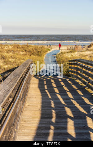 Vista oceano disegnare una giovane donna attraverso una passeggiata a mare e sulla spiaggia di sabbia Foto Stock
