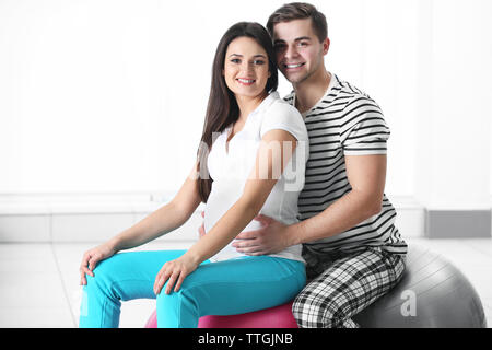 Donna incinta con il marito seduto su una sfera di fitness in camera Foto Stock